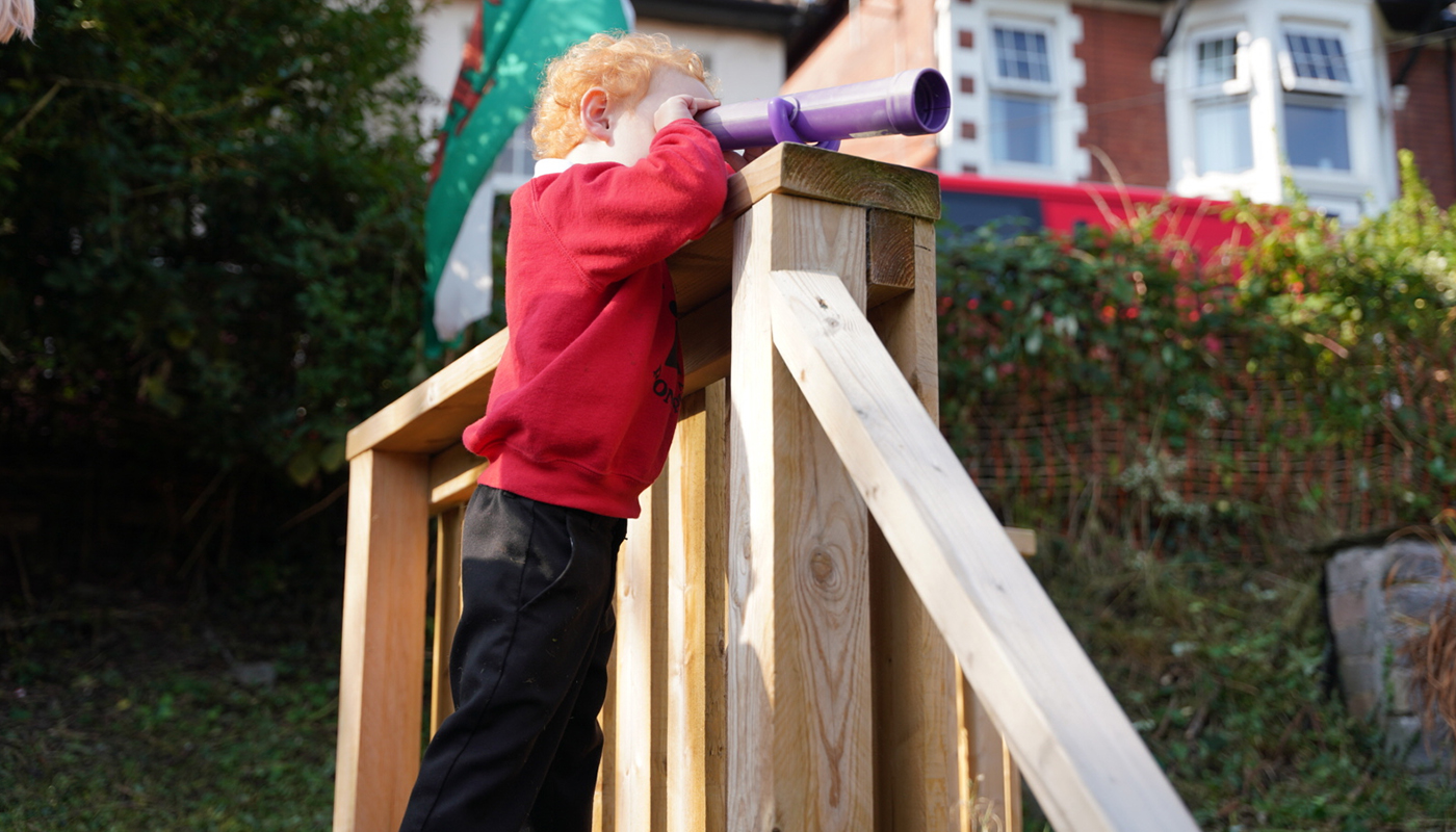 Young pupil looking through a telescope 