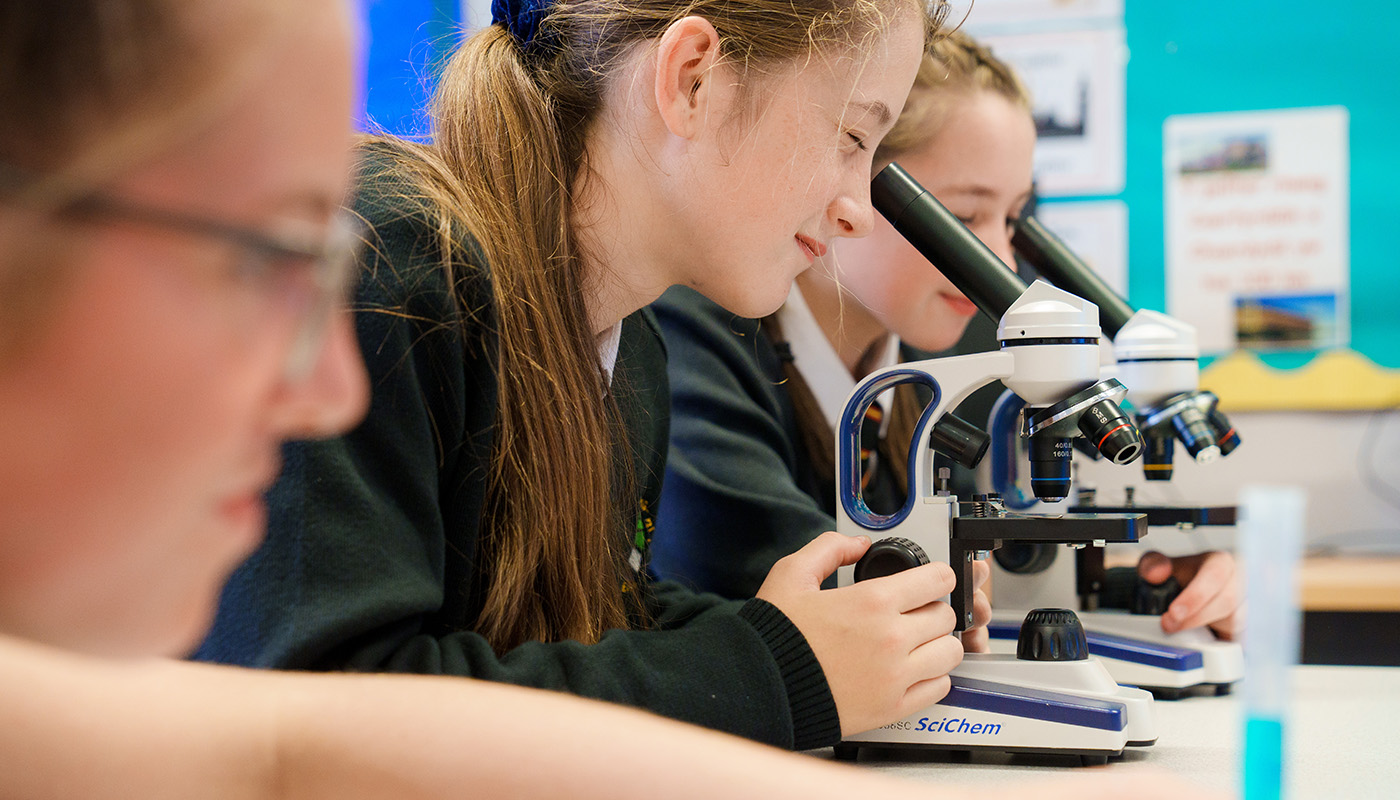 School pupils looking through microscopes