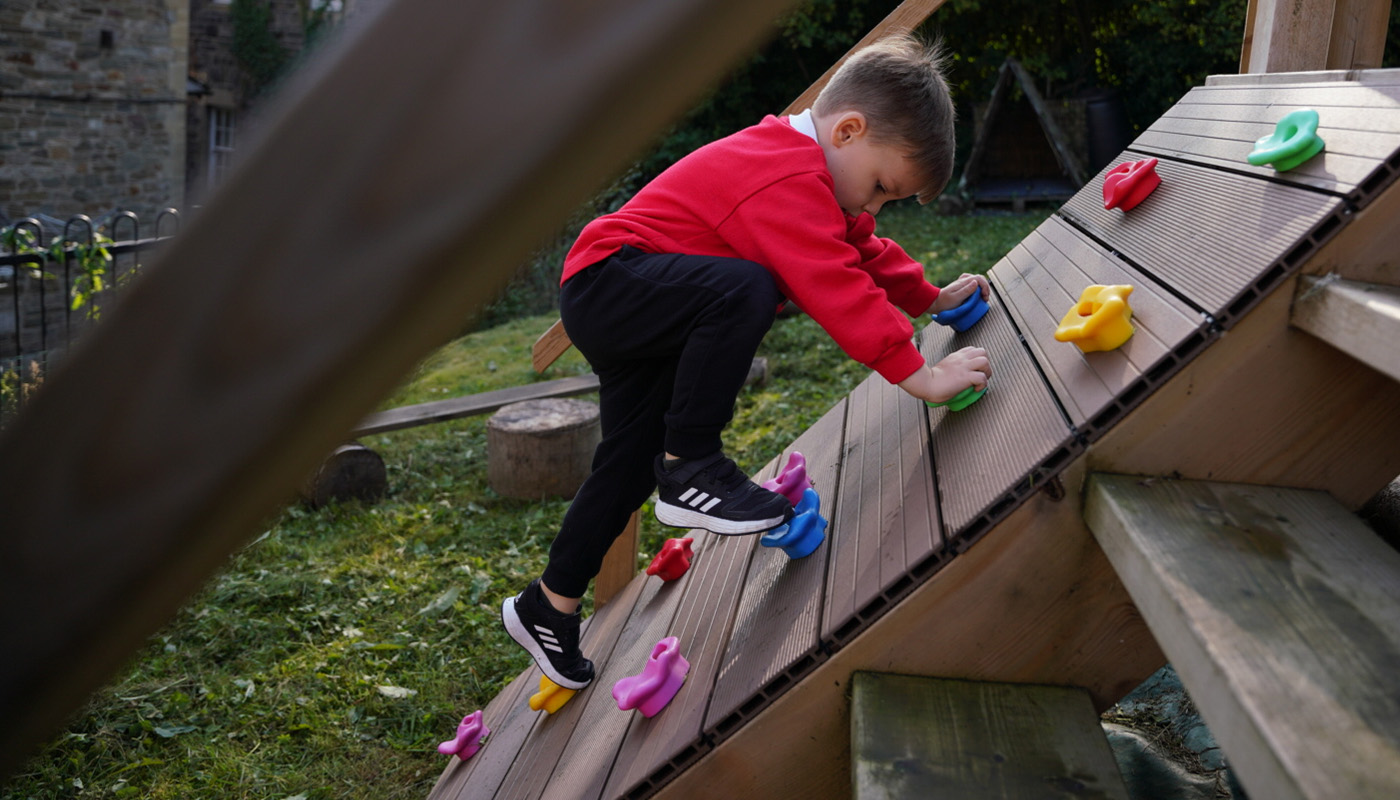 A young child on a climbing wall outside