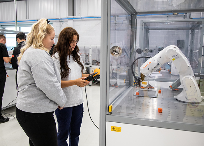 Two women operating a robotic arm