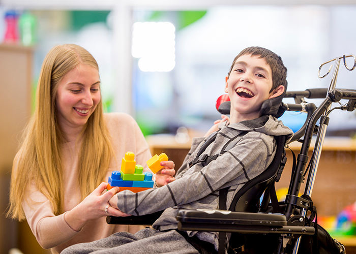 Smiling child in a wheelchair with an adult