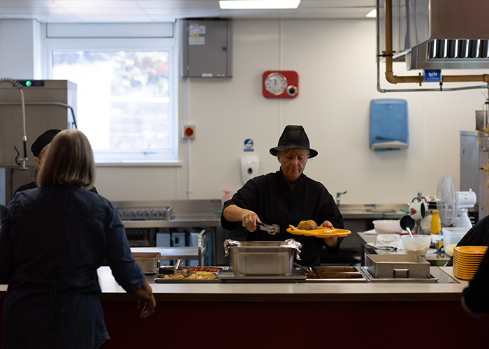 A dinner lady serving food in a school canteen