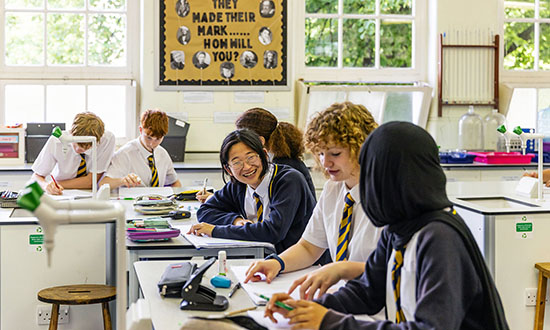 A classroom of teenagers in school uniform working together at their desks
