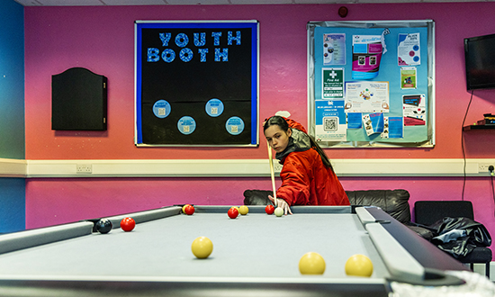 A girl holding a pool stick at a pool table
