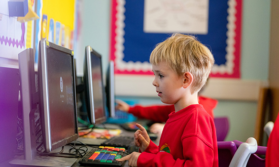 Young boy working at a computer in a classroom