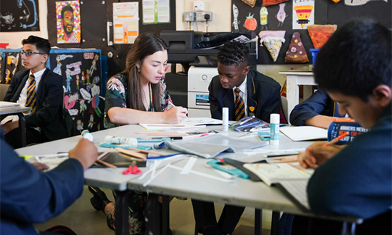 Pupils sitting around a table working with a teacher
