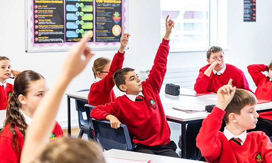 School pupils in a classroom environment raising their hands