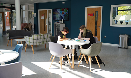Two people sitting at a table in a communal area