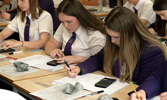 Schoolgirls working at desks with calculators