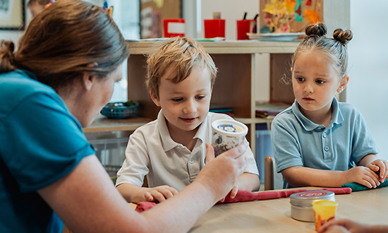 Two very young children playing with play-doh with an adult