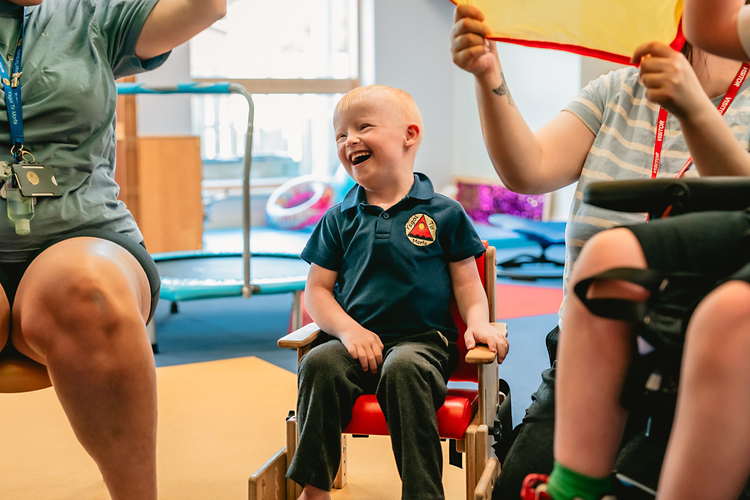 Child laughing sitting on a chair with staff