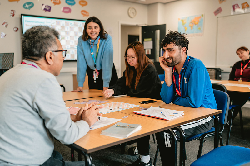 Adult learners at a table with staff